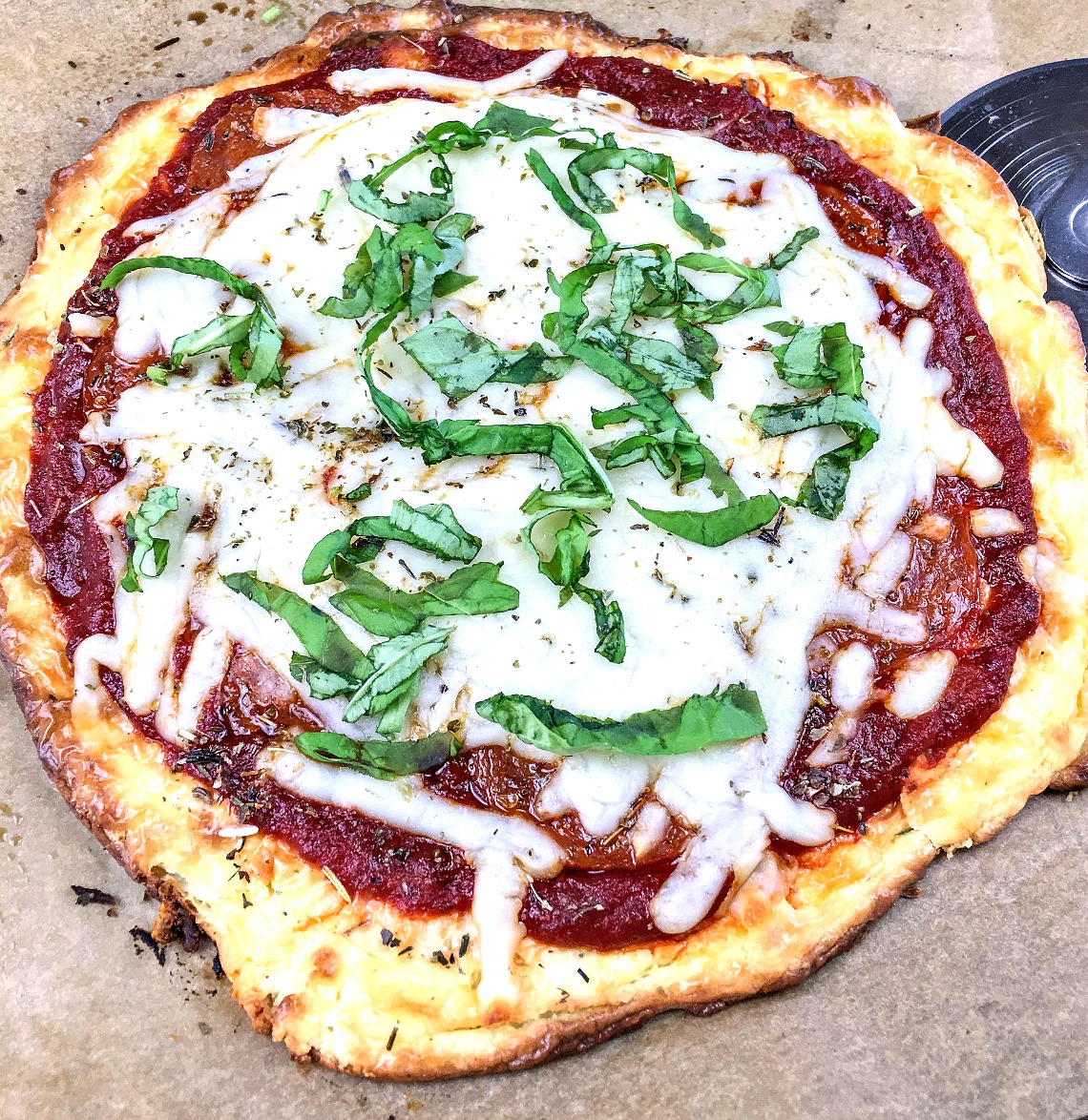 Keto pepperoni pizza topped with fresh basil