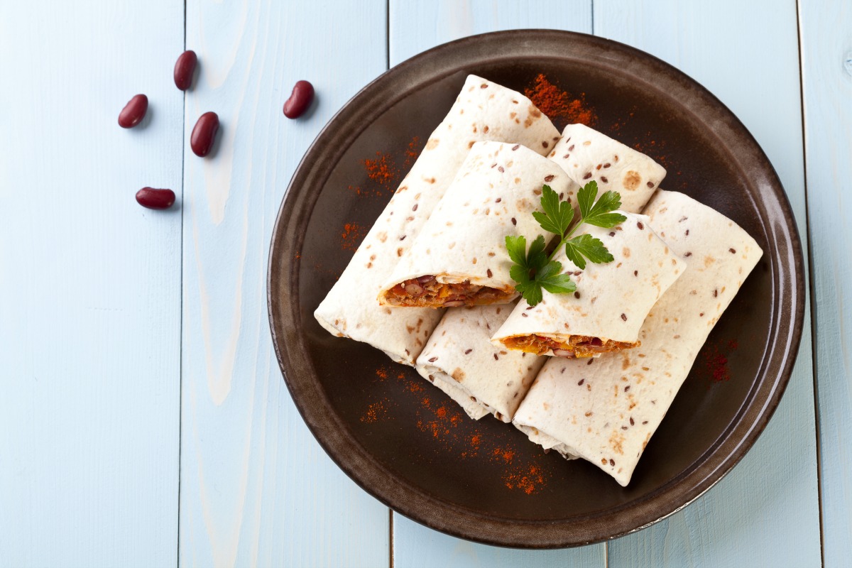 Burritos on a brown plate on a white table